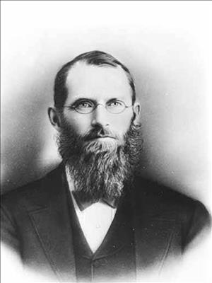 Photographic portrait of missionary and scholar Myron Eells, with a full beard and wire-rim glasses