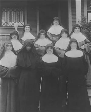 Black and white image of ten nuns standing on a porch