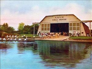 Colorized photograph of ASUW Shell House on Montlake Cut, with several rowing shells in water and on shore, ca. 1931