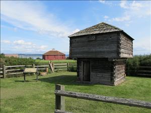 Heavy timbered blockhouse from Crockett Farm in foreground, red barn in background, located in Ebey's Landing National Historical Reserve