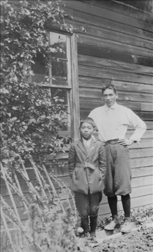 Two young Japanese-American boys standing next to a wooden building