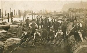 A large group of men, some white and some Japanese, sitting and standing on large logs floating in the water