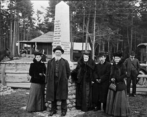 Group in dark clothing beside an obelisk that reads Adults, Arthur A. Denny and Wife, John N. Low and Wife, Carson O'Boren and Wife, William H. Bell and Wife, Louisa Boren, Erected by the Washington State Historical Society, November, 1905