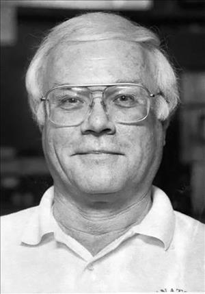 Black and white portrait of Bernier in wire frame glasses and polo shirt