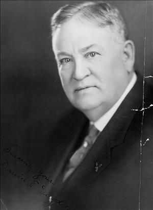 An older Dugdale posing in a dark suit and parted hair