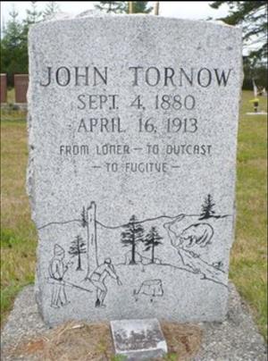 A headstone with an illustration of two pioneers holding rifles with a bear drinking by the stream in the distance and the text John Tornow, Sept. 4 1880 - April 16, 1913, From loner - to outcast - to fugitive"