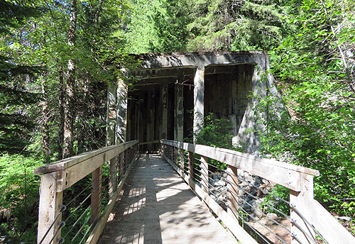 A wooden walkway through the forest leads to the entrance to a tunnel, part of the Iron Goat Trail near Stevens Pass and once the route of the Great Northern Railroad