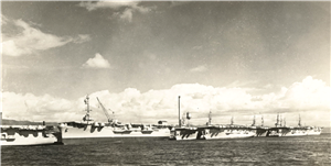 Four large war ships docked in a row with a cloudy sky above