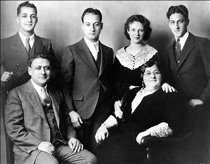 A family of six posing in formal wear in front of a studio backdrop
