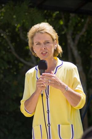 Gregoire speaking into a microphone outside in a yellow and blue shirt